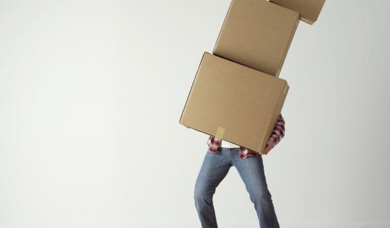 Man precariously balancing a pile of cardboard boxes